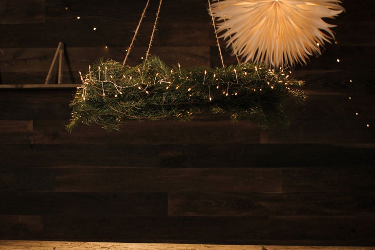 Hängender Adventskranz mit Beleuchtung und Papierstern vor Holzwand