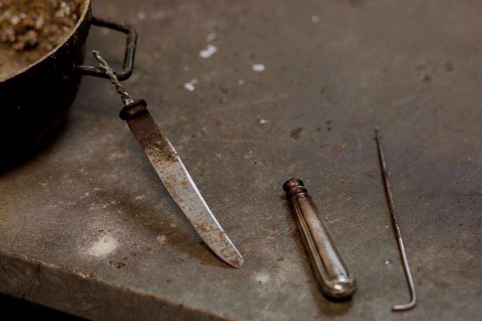 
				Das Heft ist nun von der Klinge getrennt, einer der Arbeitsschritte bei der Restaurierung eines Silbermessers in der Altonaer Silber Werkstatt. Der Teil oben an der Klinge, der im Heft steckte, heißt Erl.

			