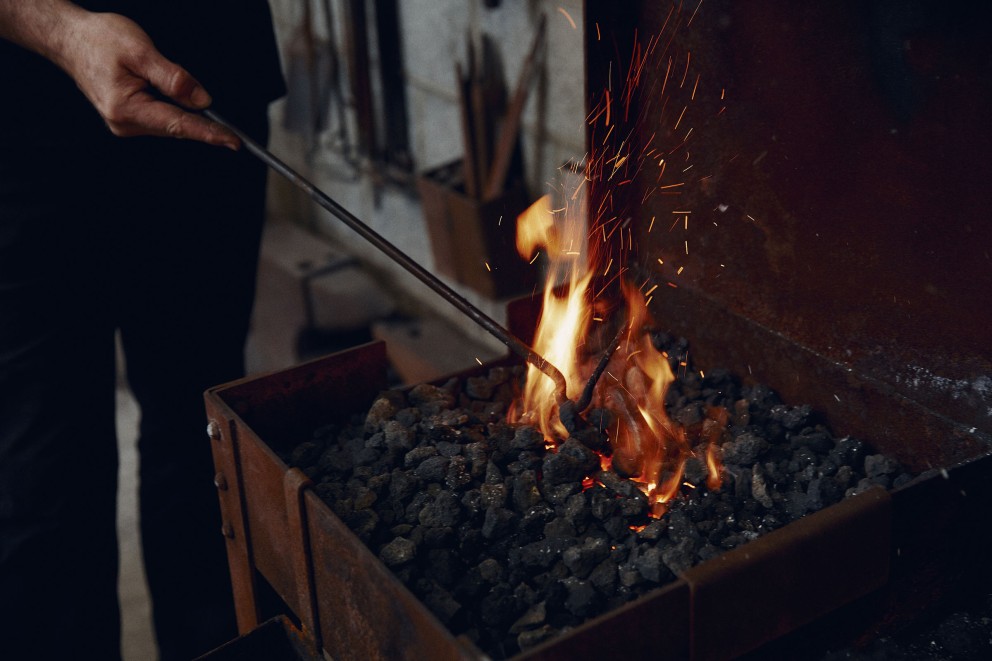 Schürhaken in der Glut der Esse. Flammen steigen aus der Glut. Schürhaken in der Glut der Esse. Flammen steigen aus der Glut.