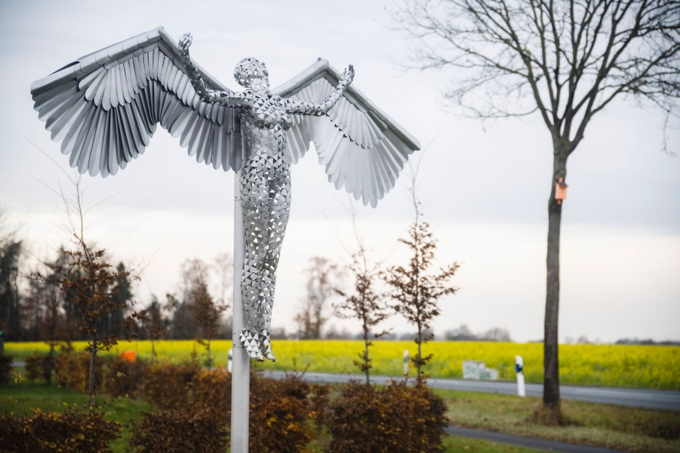 Engelsfigur aus Edelstahl an einer Stange, die in der Landschaft steht. Engelsfigur aus Edelstahl an einer Stange, die in der Landschaft steht.