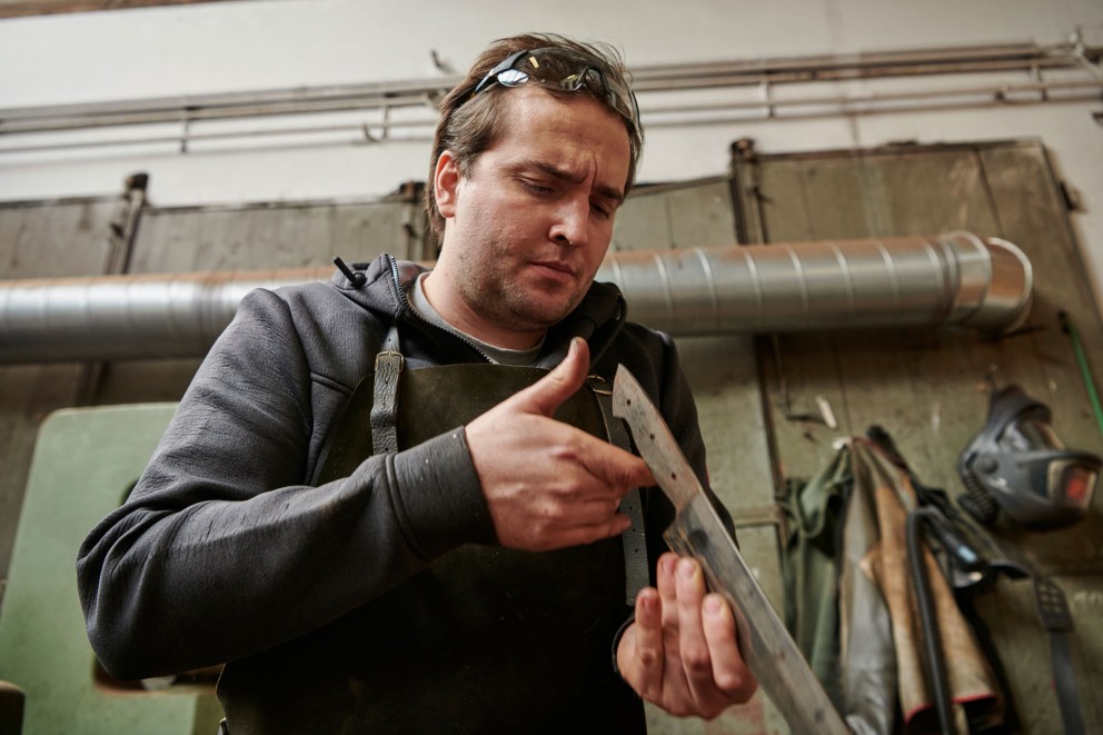 Florian hält ein Messer in der Hand und prüft die Klinge genau. Florian hält ein Messer in der Hand und prüft die Klinge genau.
