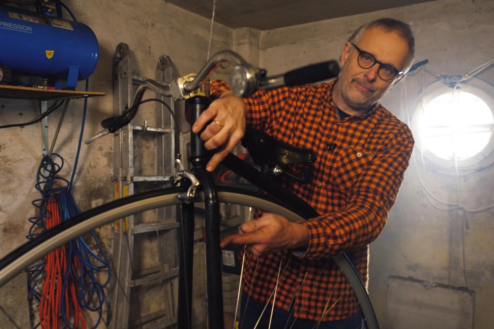 
				Bernhard zeigt die lange Fahrradgabel des Hochrads.

			