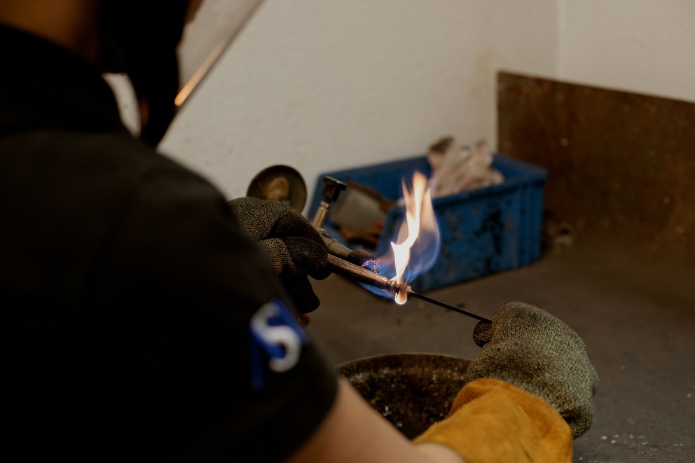 
				Fabian, Messerschmied in der Altonaer Silber Werkstatt, lötet das Heft aus – das heißt, er trennt den Griff von der Klinge.

			