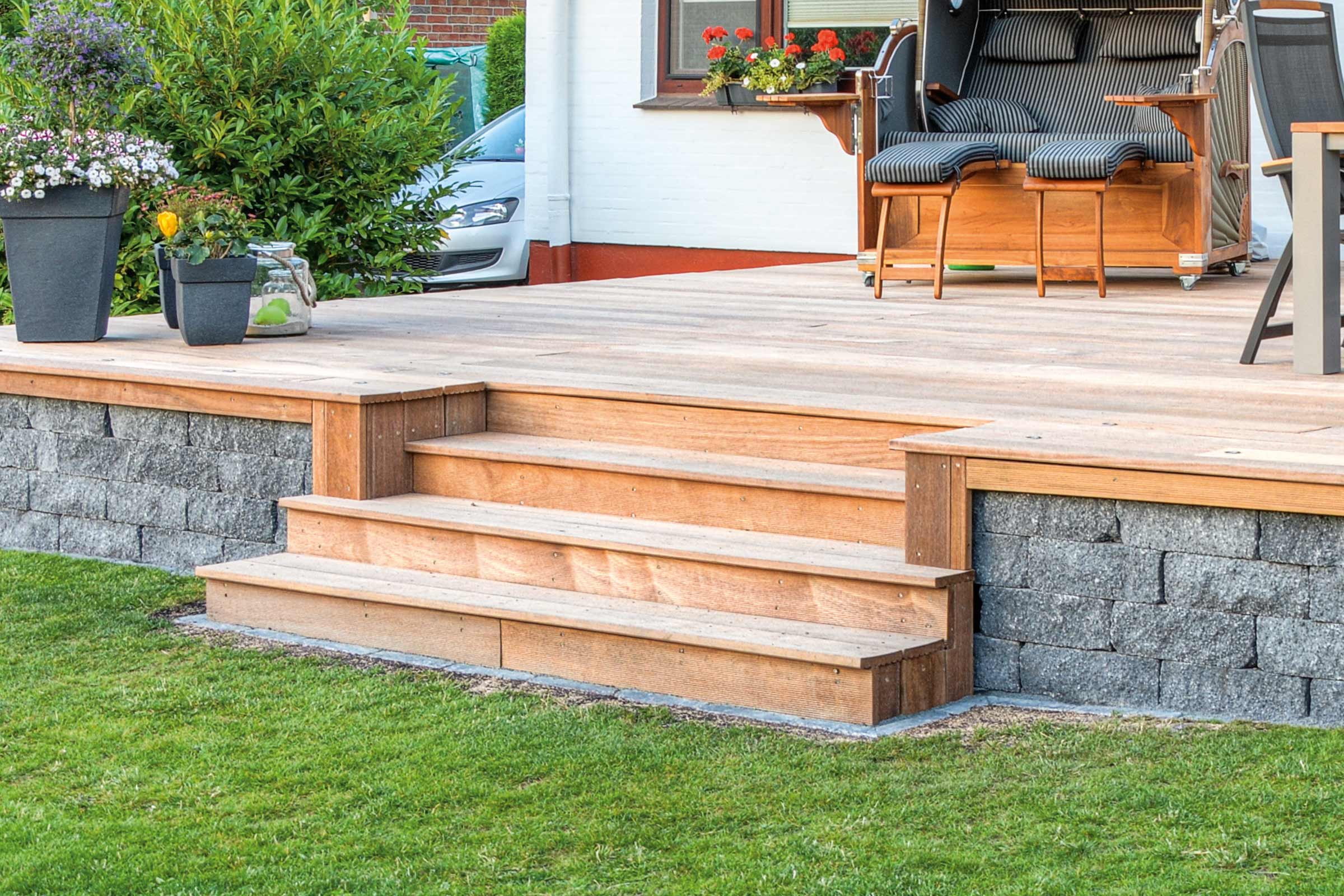 Terrasse avec marches en bois, mur et chaise de plage dans le jardin