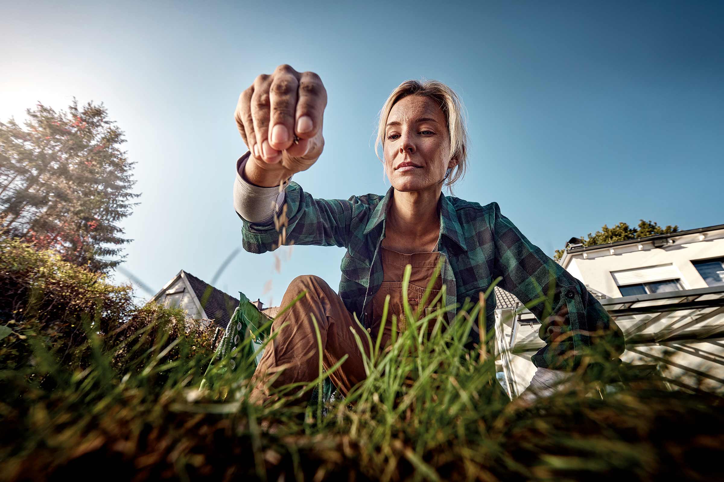 Femme semant des graines de gazon dans le jardin.