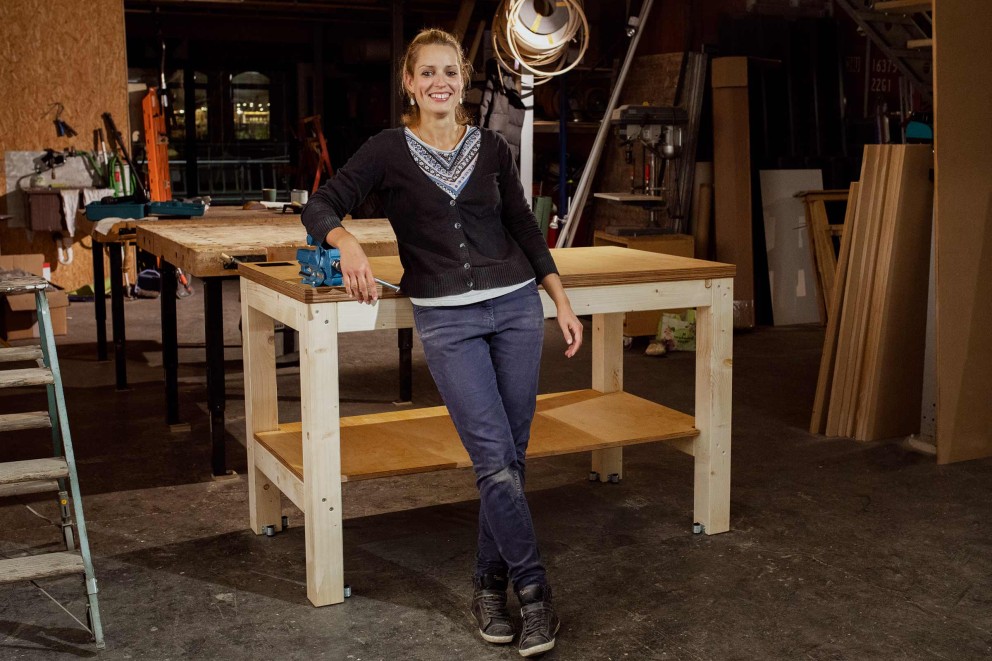 Autorin Esther Acason steht stolz vor ihrer selbst gebauten Werkbank.