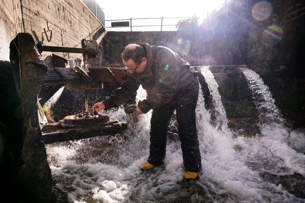 
				Nasse Ernte: Stefan steht im rauschenden Wasser und prüft die Kugeln, die im geöffneten Mahlwerk liegen.

			