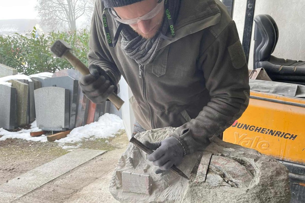 
				Alexander Macher arbeitet mit Hammer und Meißel die Details seiner Skulptur heraus.

			