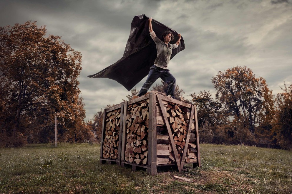 Femme debout sur une pile de bois tenant une bâche