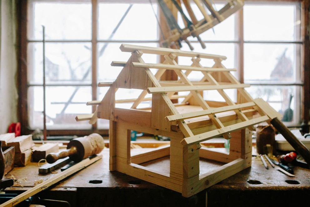 Halb fertiges Modell eines Bauernhauses aus Holz auf einer Werkbank. Halb fertiges Modell eines Bauernhauses aus Holz auf einer Werkbank.