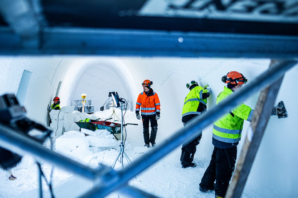 
				Architekt Luca Roncoroni in einem langen Raum im „Ice Hotel“. Zwei Arbeiter streichen die Eiswände glatt.

			