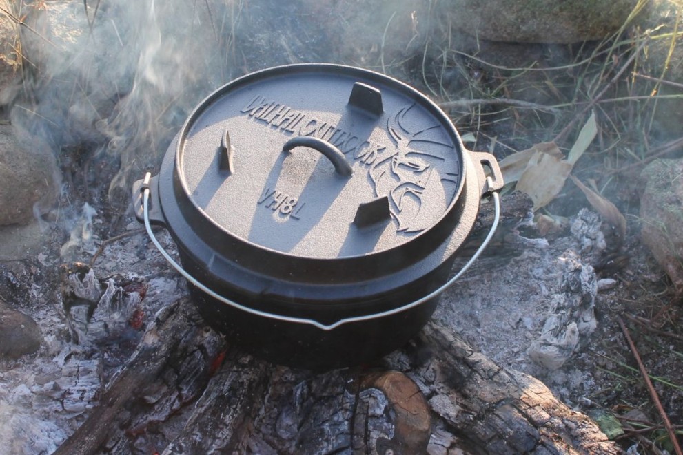 Gusseiserner Topf mit Deckel auf Lagerfeuerstelle