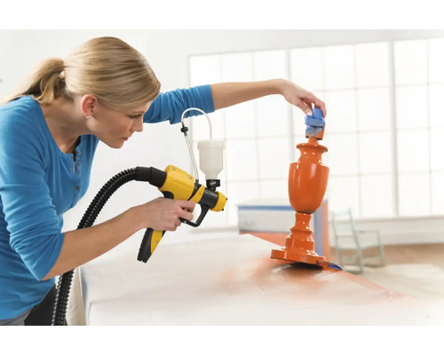 Une femme utilise un pistolet à peinture pour peindre un objet.