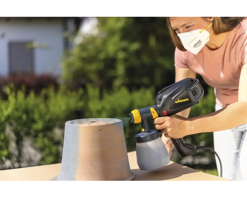 Femme pulvérise un pot avec un système de pulvérisation de peinture à l''extérieur