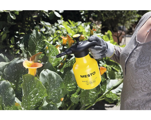 Eine Person verwendet eine gelbe Mesto Drucksprühflasche zur Pflanzenpflege.