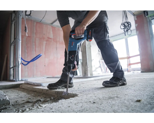 Un homme utilise un marteau-piqueur sur un chantier.