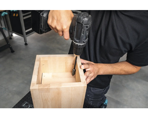 Handwerker schraubt ein Holzmöbelstück mit einem Akkubohrer zusammen