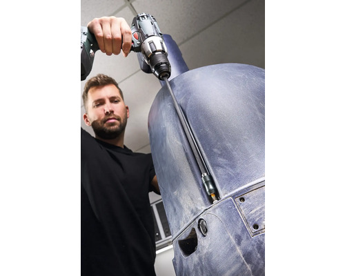 Ein Mann schraubt mit einem Akkubohrer an einem Bauteil aus Kunststoff.