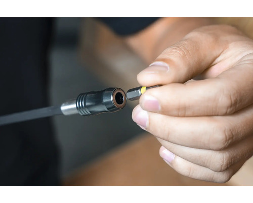 Eine Hand setzt einen Schrauberbit in einen Bithalter ein.