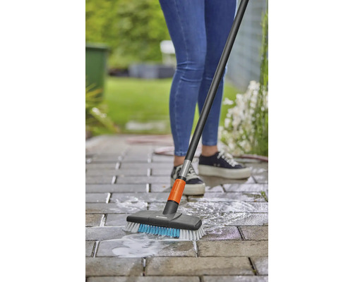 Personne nettoyant des pavés avec une brosse de surface