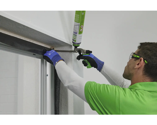 Un homme utilise un pistolet applicateur de mousse pour installer une porte.