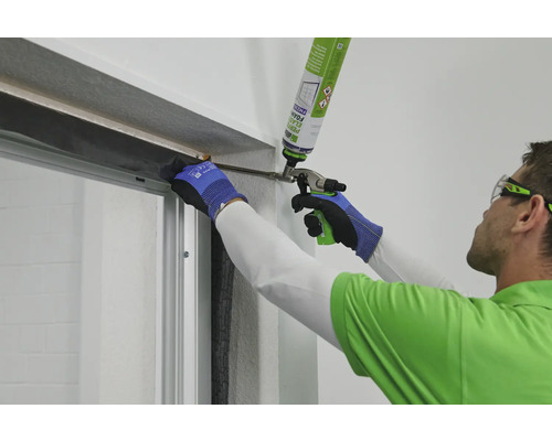 Handwerker dichtet Fenster mit Bauschaum ab.