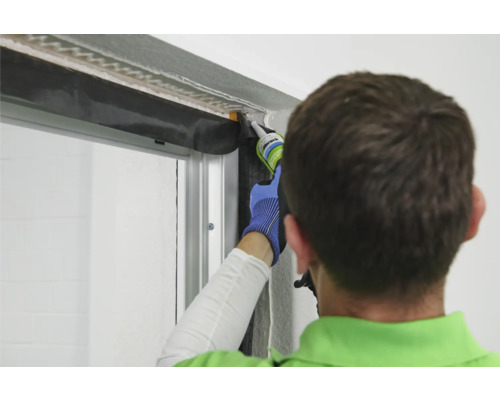 Handwerker dichtet Fenster mit Dichtstoff ab