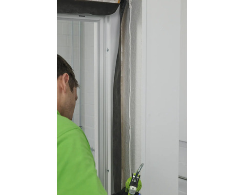 Artisan scellant un cadre de porte avec du produit d''étanchéité