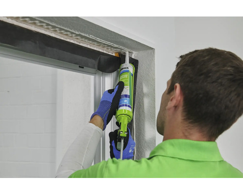 Un homme scelle une fenêtre avec du mastic.