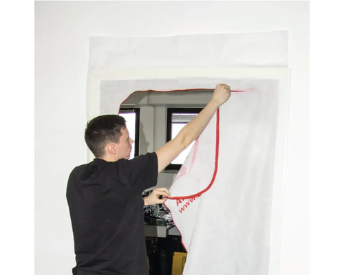 Person befestigt Staubschutzfolie an einem Fensterrahmen