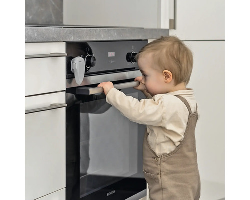 Enfant essaie d''ouvrir un four avec sécurité enfant