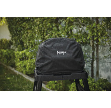 Schwarze Ninja Grillabdeckung auf einem Grillständer im Regen.