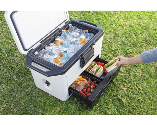 Tragbare Kühlbox mit Eis, Getränken und herausziehbaren Schubladen für Lebensmittel auf Gras.