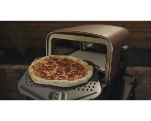 Pizza sur une pelle à pizza devant un four à pizza