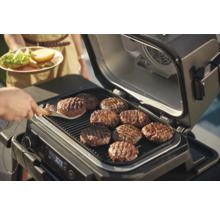 Gril électrique avec plusieurs galettes de hamburger sur la grille.
