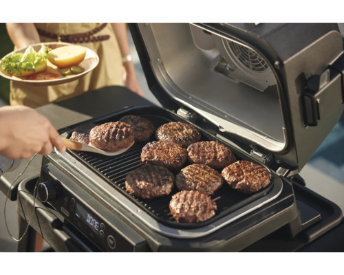 Elektrischer Grill mit mehreren Burger Patties auf dem Rost.