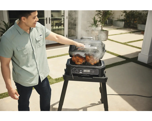 Mann grillt Hähnchen auf einem elektrischen Ninja Grill im Freien.