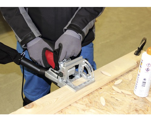 Une personne utilise une fraise à lamelles sur une planche de bois.