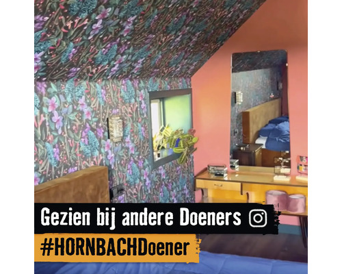 Chambre à coucher avec papier peint à motifs floraux sur les murs et le plafond, fenêtre, miroir et commode.