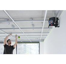 Ein Mann installiert eine abgehängte Decke mit einem Linienlaser zur präzisen Ausrichtung.