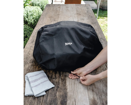 Schutzhülle für Grill mit Ninja Logo auf einem Holztisch
