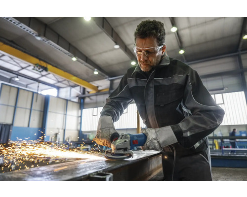 Handwerker schleift Metall mit einem Winkelschleifer in einer Werkstatt.