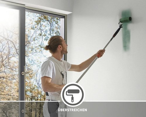 Ein Mann streicht eine Wand mit einer Farbrolle an einem Teleskopstiel
