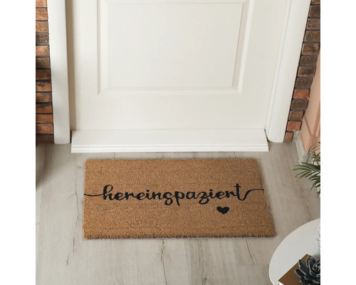 Paillasson en fibre de coco avec l''inscription ''hereinspaziert'' et un symbole de cœur devant une porte