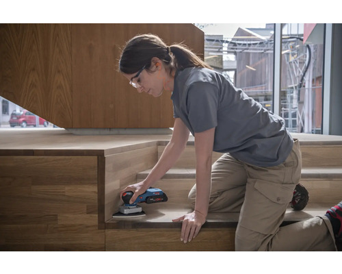 Femme ponçant un escalier en bois avec une ponceuse