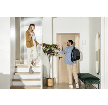Hall d''entrée lumineux avec escalier, vestiaire et deux personnes qui se disent au revoir.