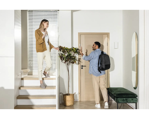 Heller Eingangsbereich mit Treppe, Garderobe und zwei Personen, die sich verabschieden.