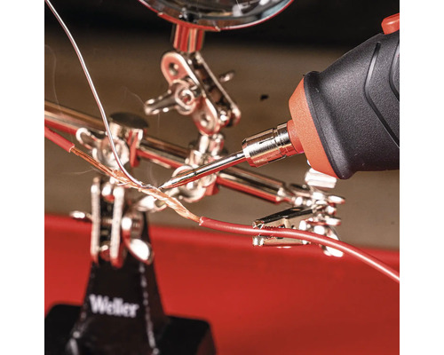 Soudure de câbles avec un fer à souder dans un support avec loupe.