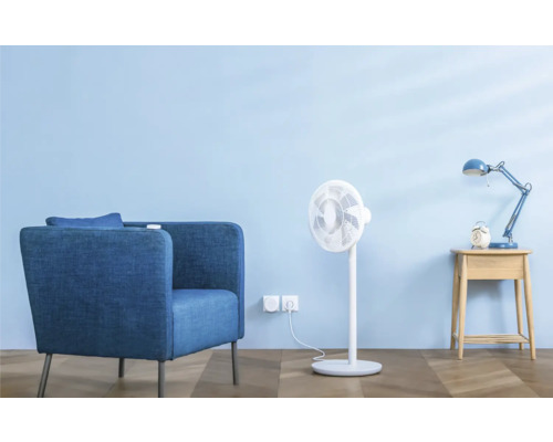 Scène de salon avec fauteuil, ventilateur, lampe de chevet et réveil