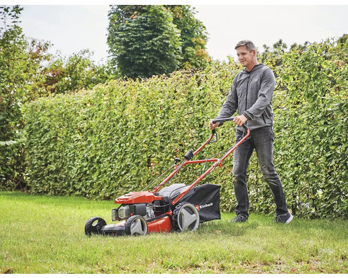 Ein Mann schiebt einen Rasenmäher der Marke Einhell über einen Rasen